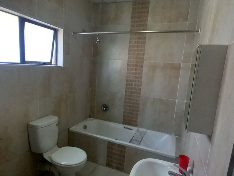 A functional bathroom featuring a bathtub, toilet, basin, and tiled finishes, offering a clean and practical space.