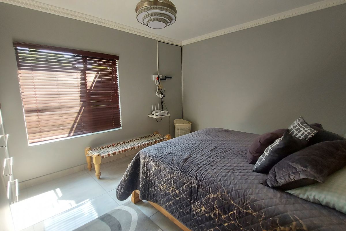 A well-maintained bedroom featuring tiled flooring, built-in cupboards, and venetian blinds, offering a clean and functional living space.