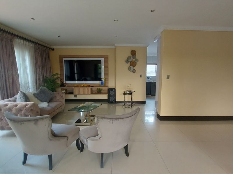 Spacious living room featuring tiled floors, recessed lighting, and a built-in media unit, with direct access to the outdoor pool area through sliding glass doors.