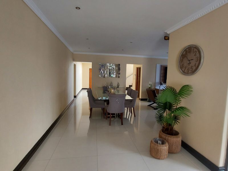 Spacious dining area featuring polished porcelain tile flooring, recessed downlighting, and decorative cove cornicing, creating a bright and open atmosphere.