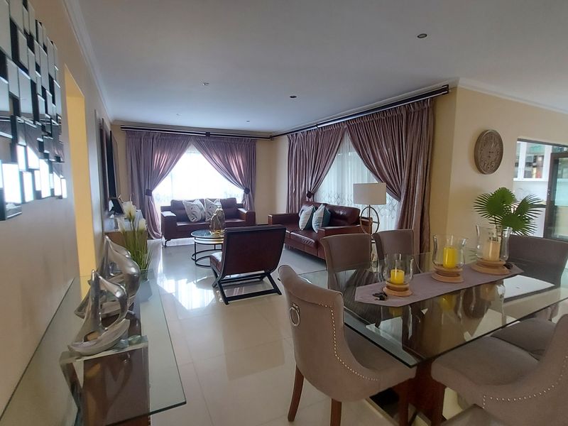 Spacious open-plan living and dining area featuring polished tiled flooring, recessed lighting, and large sliding glass doors providing natural light.