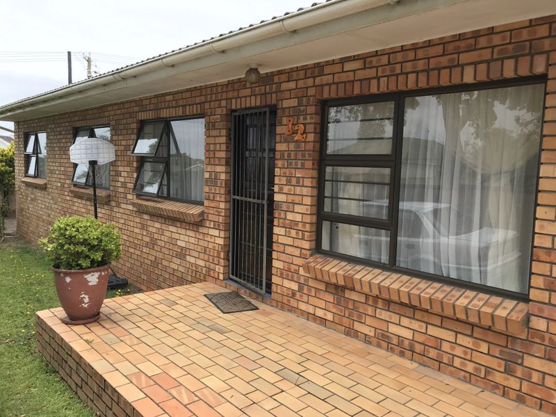 Front facade of a face brick house featuring a paved patio entrance, security gate, and aluminium window frames.