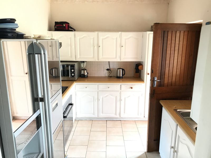 A functional kitchen featuring white cabinetry, wooden countertops, tiled flooring, and integrated appliances, offering a classic and practical layout.