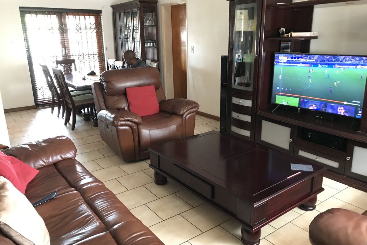 Spacious living area featuring ceramic floor tiles and a sliding glass door with security gate, providing access to the exterior.