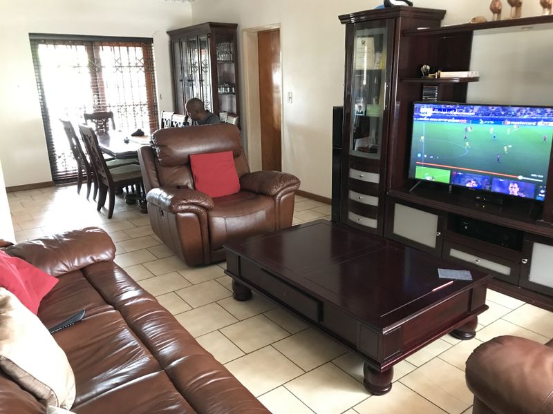 Spacious living area featuring ceramic floor tiles and a sliding glass door with security gate, providing access to the exterior.