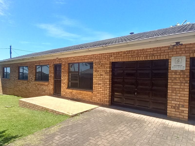 Front view of a face brick house featuring a double garage, paved driveway, and a small brick patio area.
