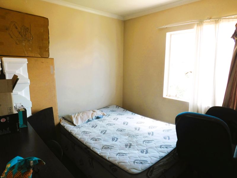 A standard bedroom featuring a window with a curtain rail and neutral wall finishes, offering a functional space for rest.