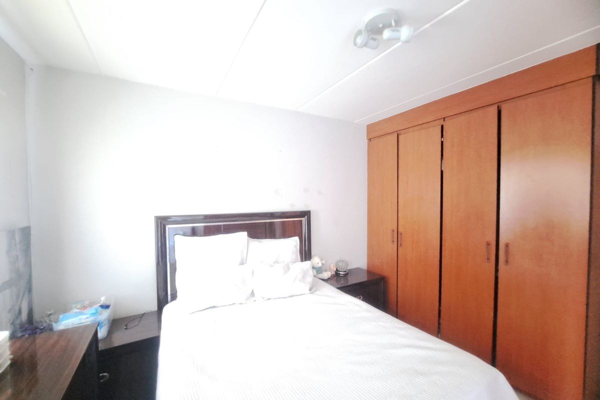 A bedroom featuring built-in wooden wardrobes and a ceiling-mounted spotlight, offering functional storage space within the apartment.
