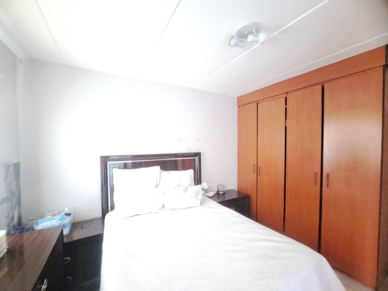 A bedroom featuring built-in wooden wardrobes and a ceiling-mounted spotlight, offering functional storage space within the apartment.