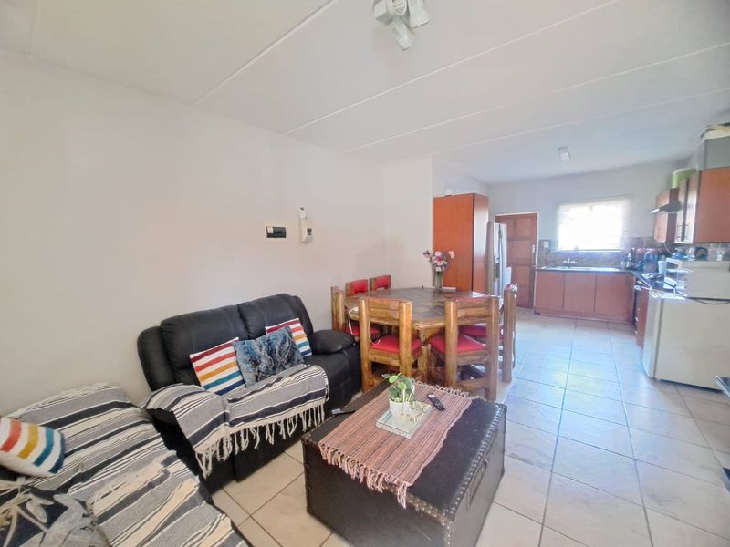 Open-plan living and dining area featuring tiled flooring and a functional kitchen with built-in cabinetry and appliances.