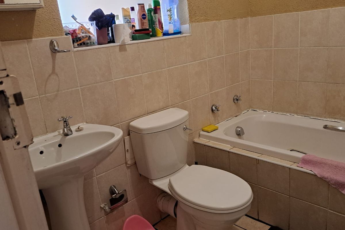 A compact bathroom featuring a pedestal basin, a standard toilet, and a built-in bathtub with tiled surround.