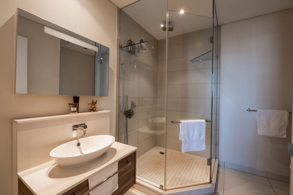 Modern bathroom featuring a glass-enclosed shower, a contemporary vessel sink vanity, and neutral wall tiling.