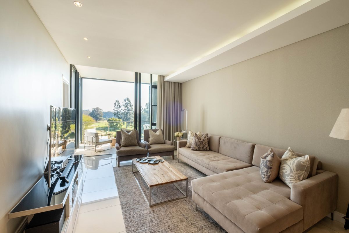 Modern living room featuring polished tile flooring, recessed ceiling lighting, and large sliding glass doors opening to a balcony with scenic views.