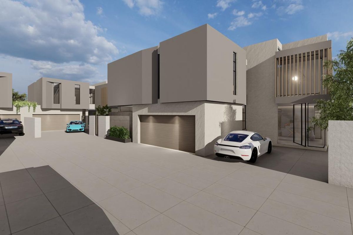 A modern cluster home exterior featuring clean architectural lines, paved driveway access, and integrated garage doors.