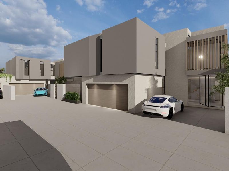 A modern cluster home exterior featuring clean architectural lines, paved driveway access, and integrated garage doors.