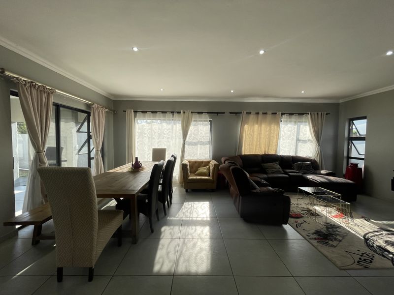 Spacious open-plan living and dining area featuring large format floor tiles, recessed lighting, and expansive sliding glass doors leading to the exterior.