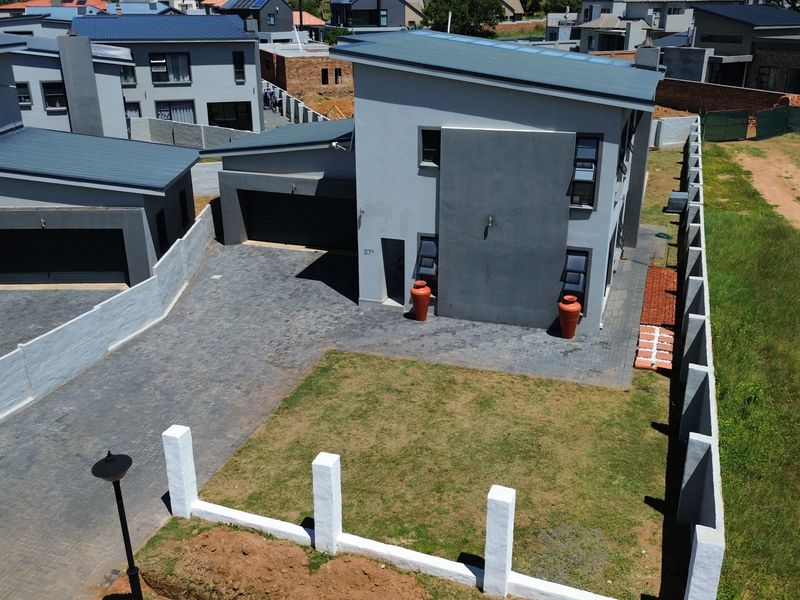 Aerial view of a modern two-story residential property featuring a paved driveway, double garage, and a private front garden with boundary walling.
