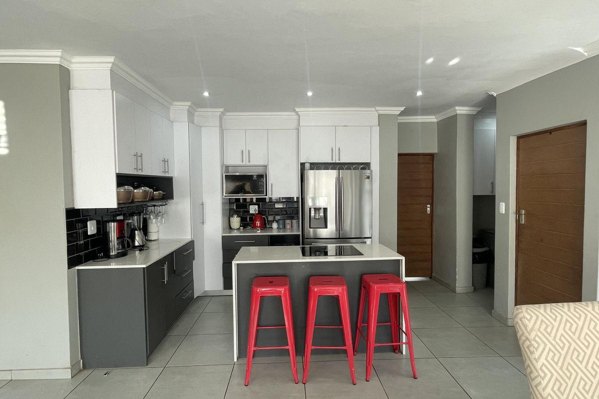 Modern kitchen featuring two-tone cabinetry, a central island with an integrated hob, tiled flooring, and recessed lighting.
