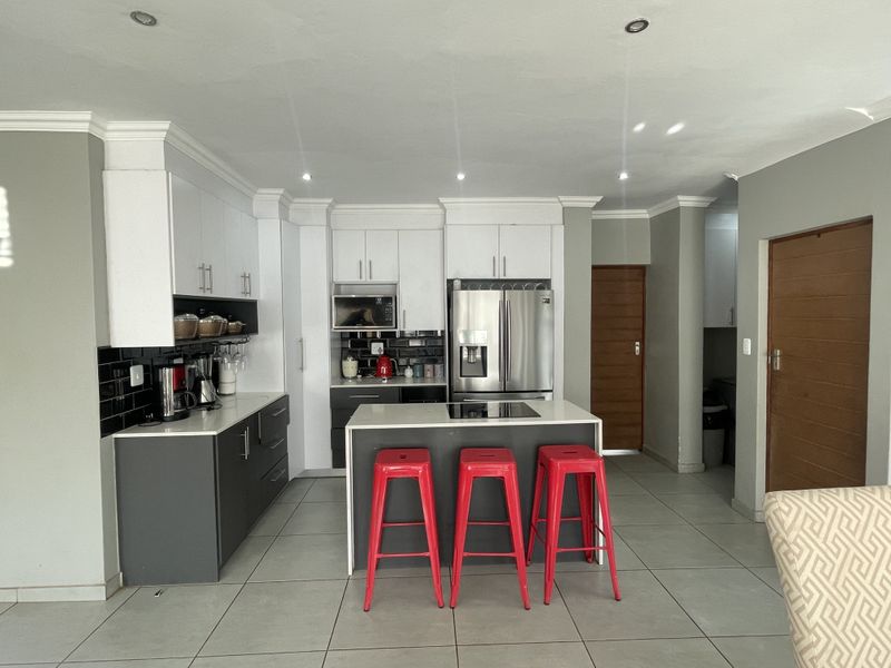 Modern kitchen featuring two-tone cabinetry, a central island with an integrated hob, tiled flooring, and recessed lighting.