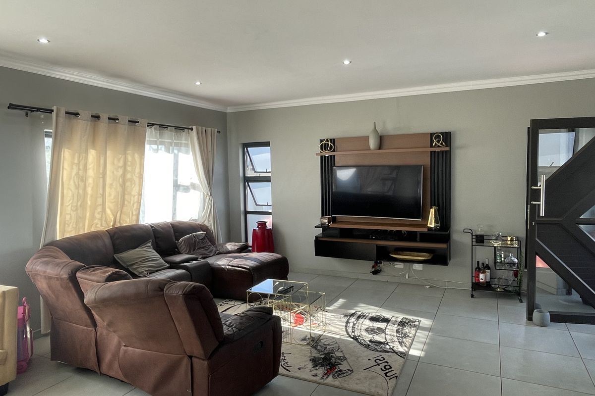 A well-maintained living room featuring tiled flooring, recessed downlighting, and a modern built-in media unit with integrated shelving.