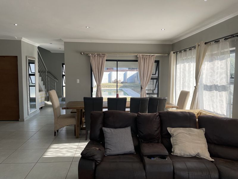 Spacious open-plan living and dining area featuring tiled floors, recessed lighting, and sliding doors providing direct access to the outdoor pool area.