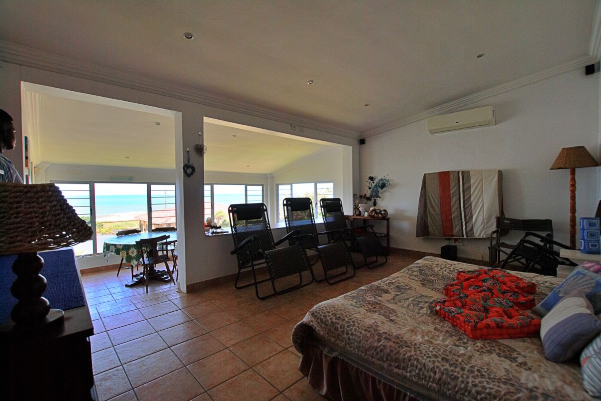 Spacious bedroom featuring tiled flooring, recessed lighting, and a split-system air conditioner, with large windows offering expansive coastal views.