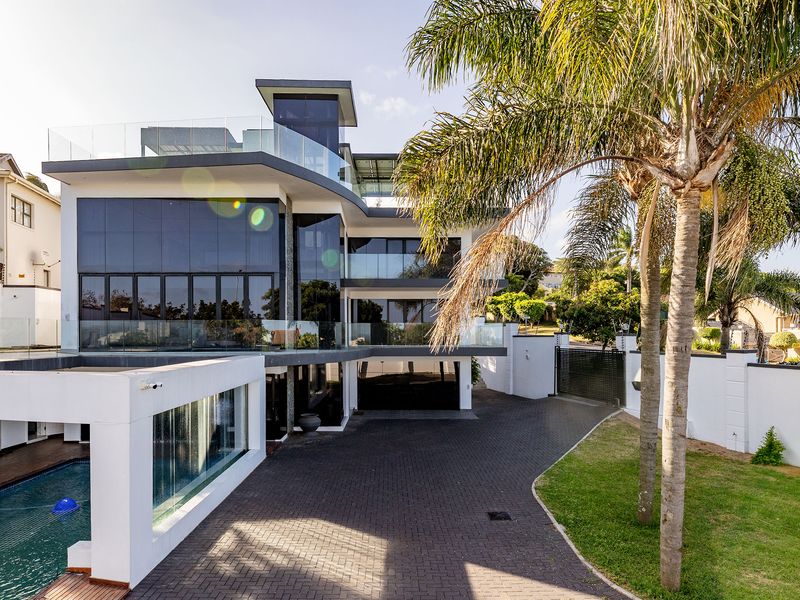 Modern multi-level luxury residence featuring a paved driveway, integrated swimming pool with glass balustrades, and contemporary architectural design.