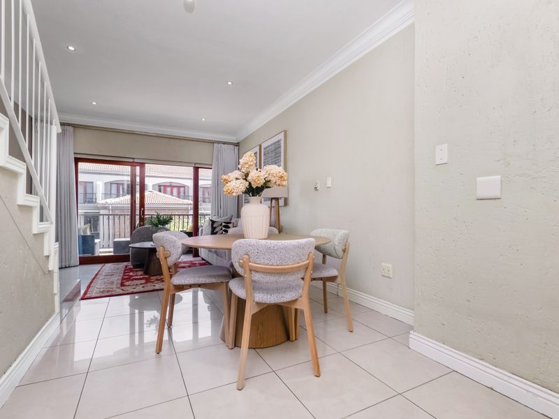 Open-plan living and dining area featuring tiled flooring, recessed lighting, and sliding glass doors leading to a balcony.