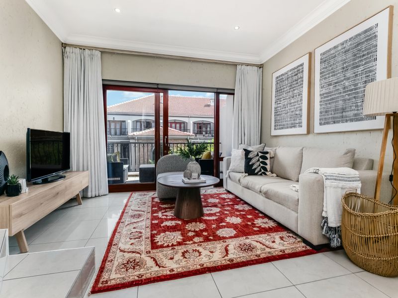 A bright and well-maintained living room featuring tiled flooring, recessed lighting, and large sliding glass doors providing access to an outdoor balcony area.