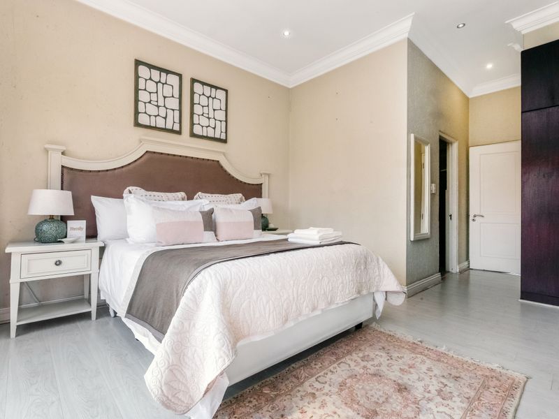 A well-maintained bedroom featuring laminate flooring, recessed downlighting, crown molding, and built-in cupboards.
