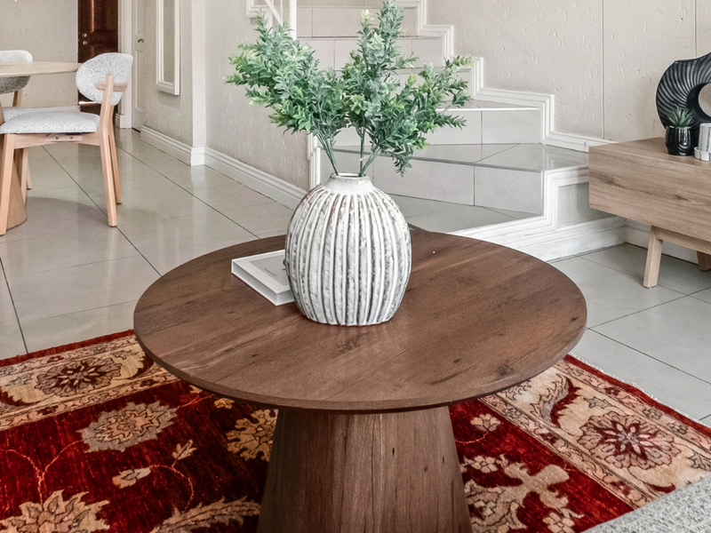 A bright living area featuring neutral tiled flooring and a staircase, creating an open and inviting atmosphere.