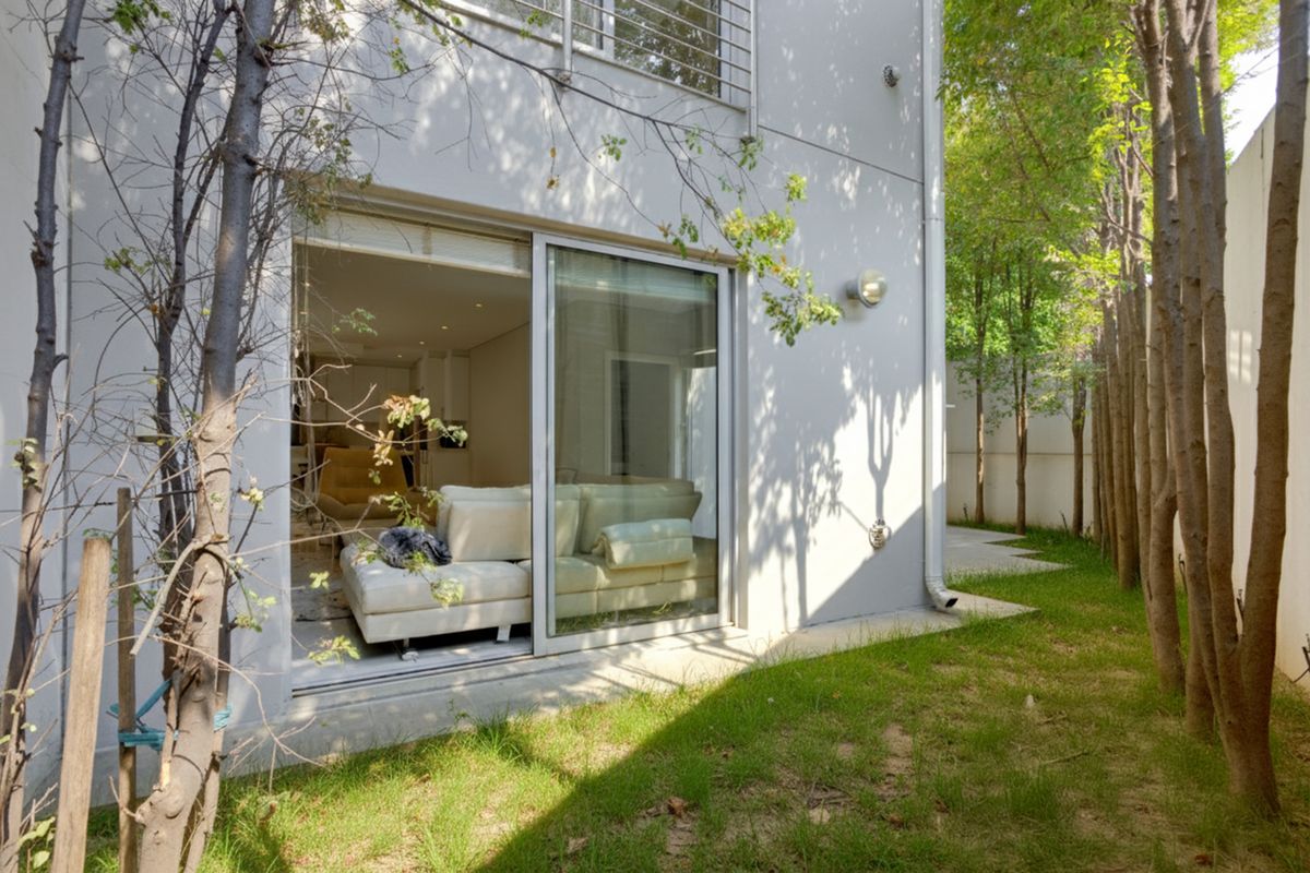 Rear view of the property featuring a small garden area, paved pathway, and sliding glass doors providing access to the interior living space.
