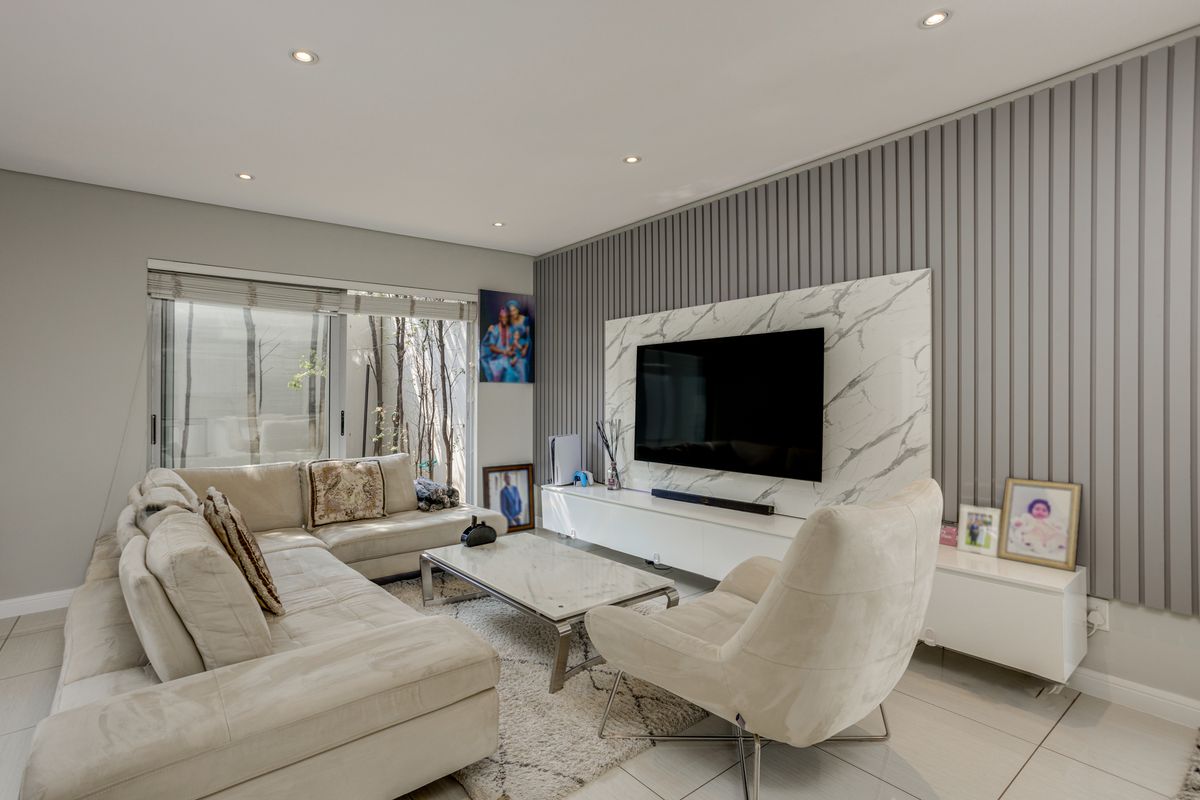 Modern living room featuring a feature wall with vertical paneling and marble-look cladding, recessed downlighting, and large sliding glass doors leading to the exterior.