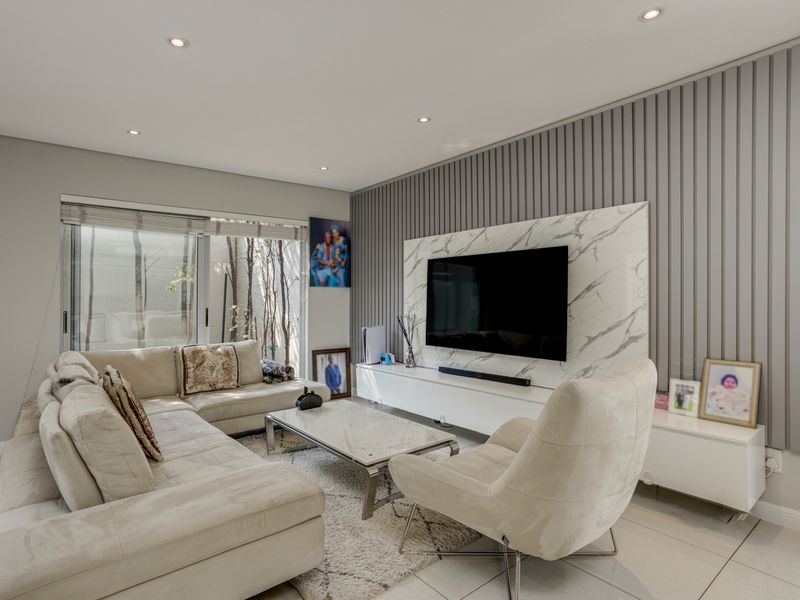 Modern living room featuring a feature wall with vertical paneling and marble-look cladding, recessed downlighting, and large sliding glass doors leading to the exterior.