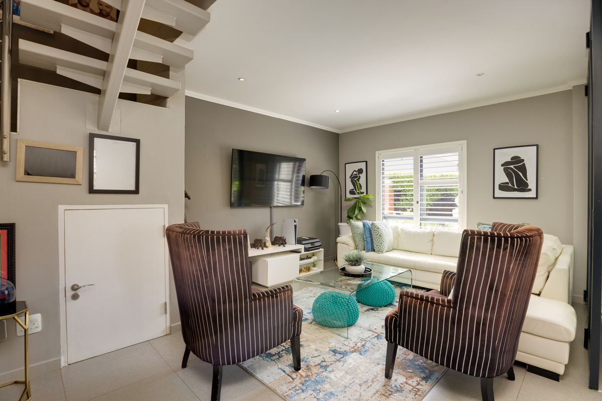 A comfortable living room featuring tiled flooring, recessed ceiling lighting, and a staircase with an under-stair storage cupboard.