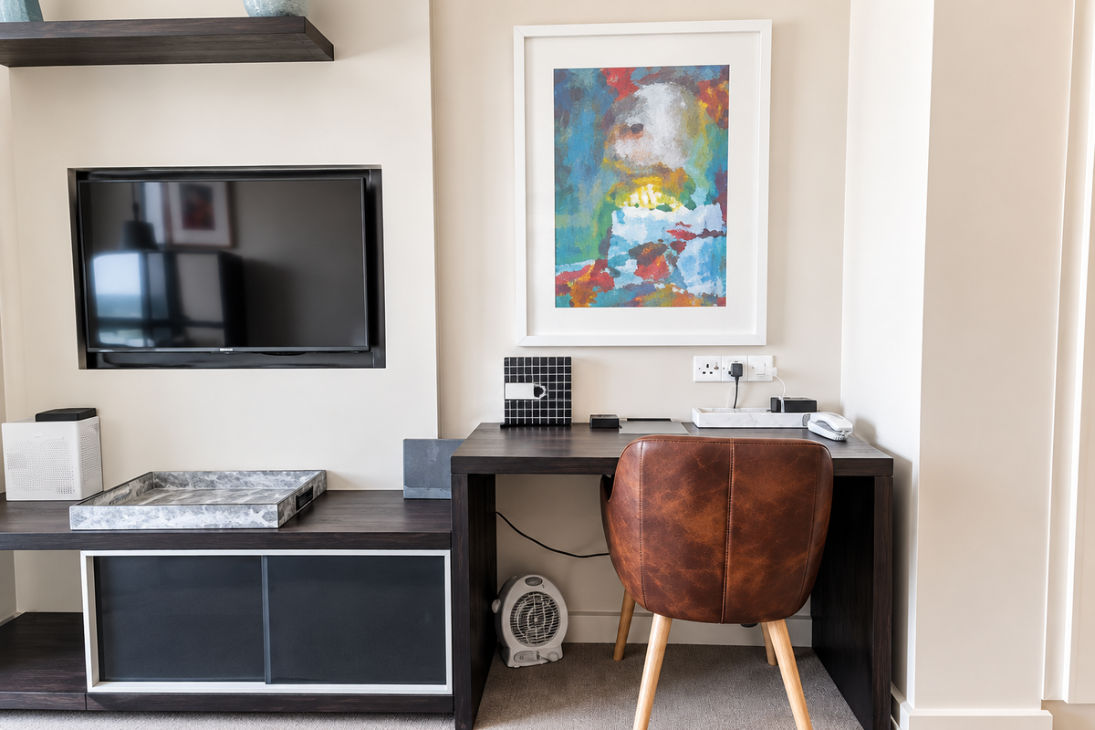 A well-maintained living area featuring a built-in media console with a recessed television niche and a dedicated workspace with integrated electrical outlets.