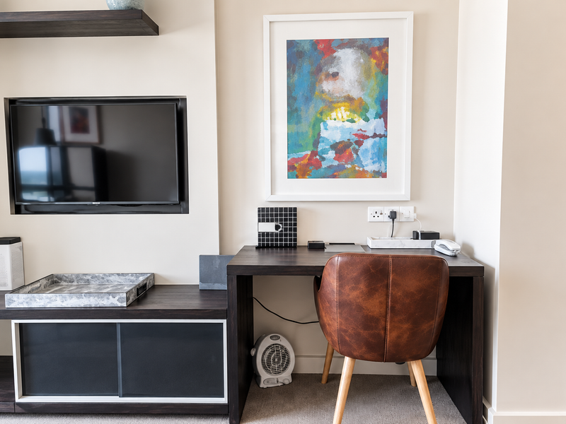 A well-maintained living area featuring a built-in media console with a recessed television niche and a dedicated workspace with integrated electrical outlets.