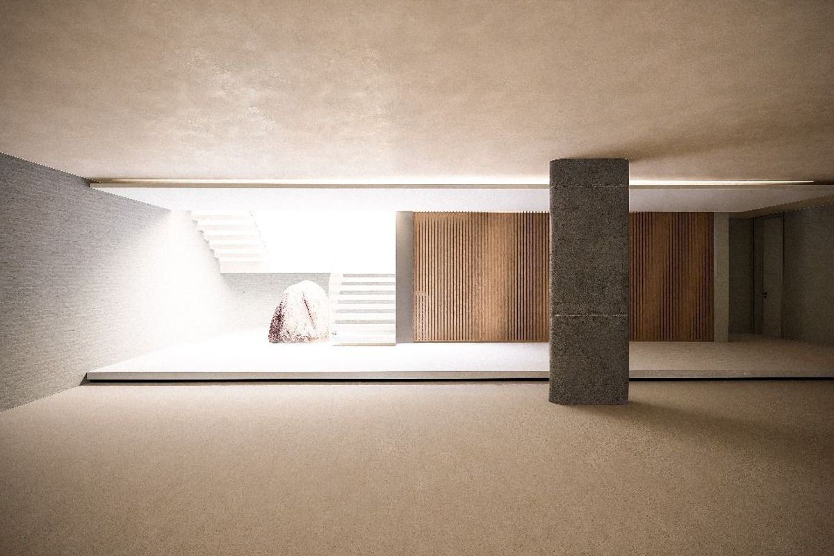 A minimalist, modern interior space featuring clean lines, a central structural column, wooden slat wall paneling, and a staircase leading to an upper level.