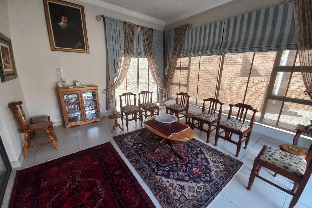 A spacious living room featuring large floor-to-ceiling windows, tiled flooring, and decorative crown molding, offering a bright and comfortable living environment.