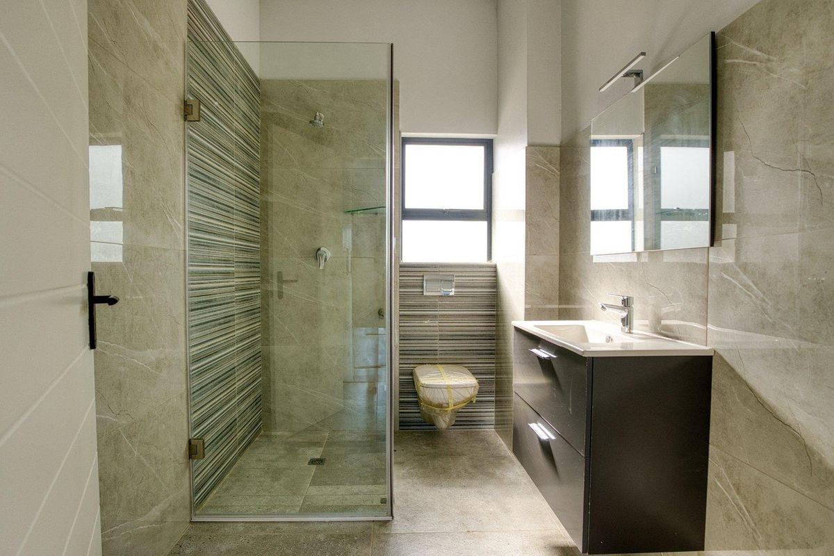 Modern bathroom featuring a glass-enclosed shower, wall-mounted toilet, and a sleek vanity with a mirror.