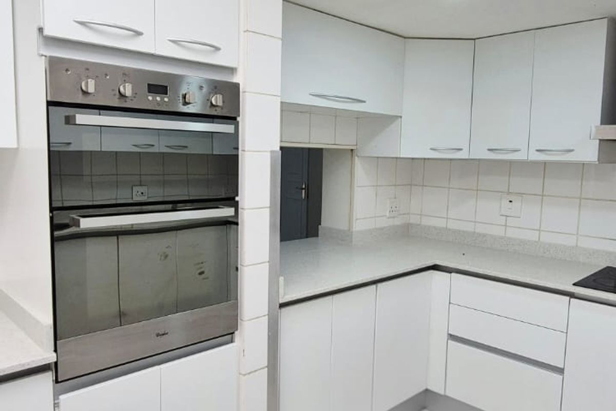 A functional kitchen featuring white built-in cabinetry, stone countertops, a built-in oven, and tiled flooring with a neutral backsplash.