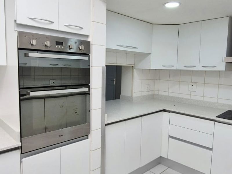 A functional kitchen featuring white built-in cabinetry, stone countertops, a built-in oven, and tiled flooring with a neutral backsplash.