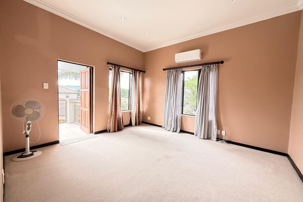 Spacious bedroom featuring neutral walls, carpeted flooring, recessed ceiling lighting, a wall-mounted air conditioning unit, and direct access to a private balcony.