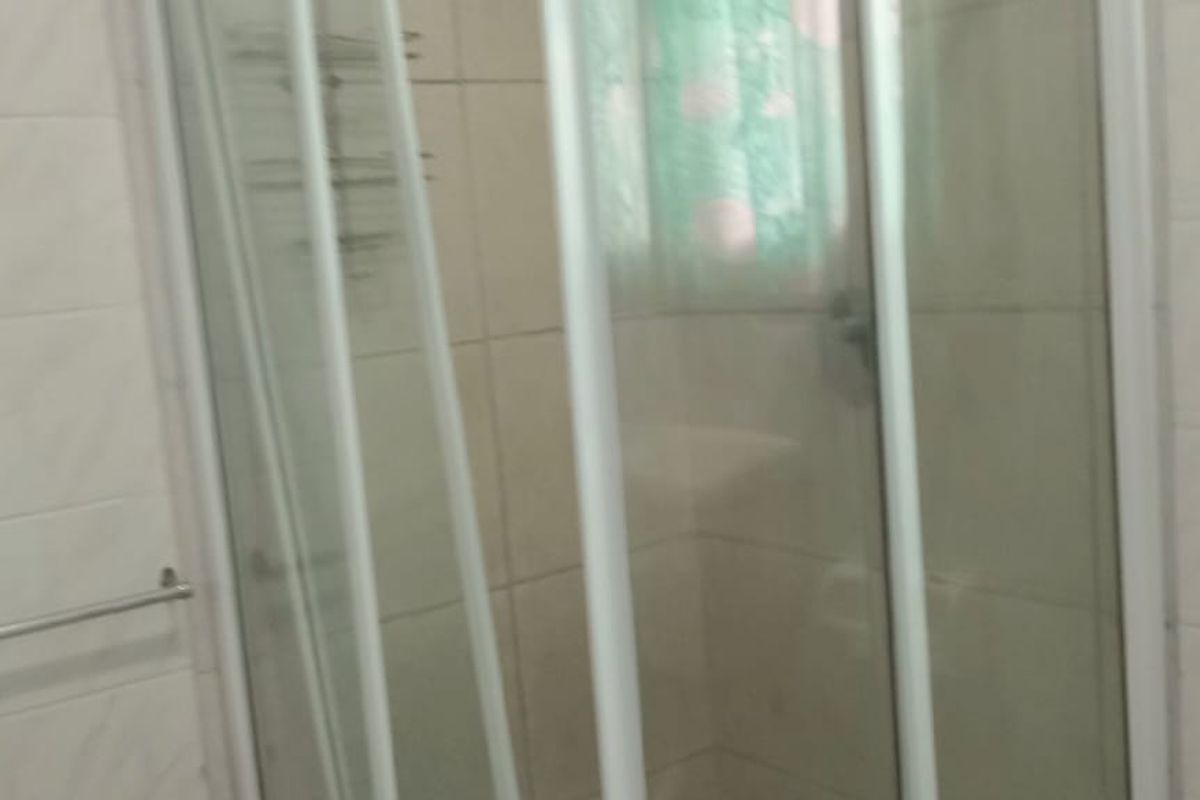 A functional bathroom featuring a glass-enclosed shower stall with white wall tiling and standard bathroom fixtures.