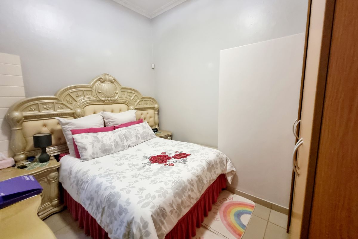 A compact bedroom featuring tiled flooring, crown molding, and a built-in wardrobe.