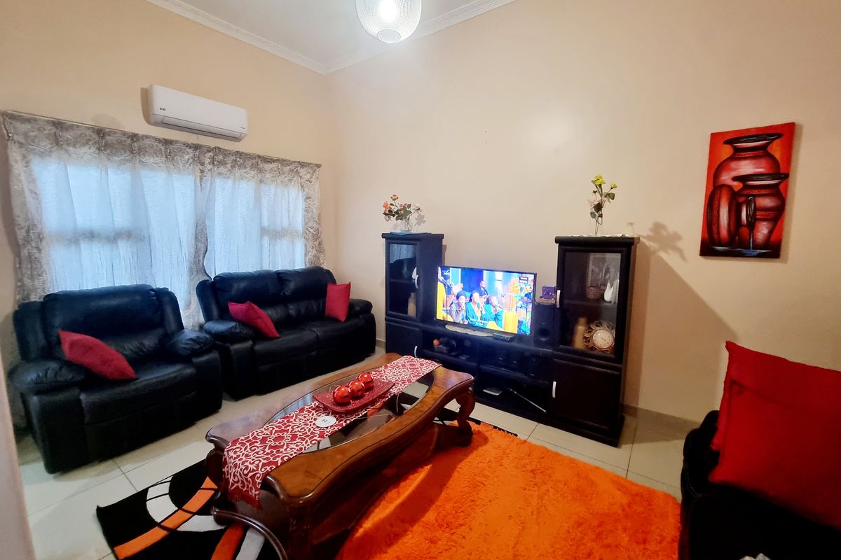 A comfortable living room featuring tiled flooring, crown molding, and a wall-mounted air conditioning unit.