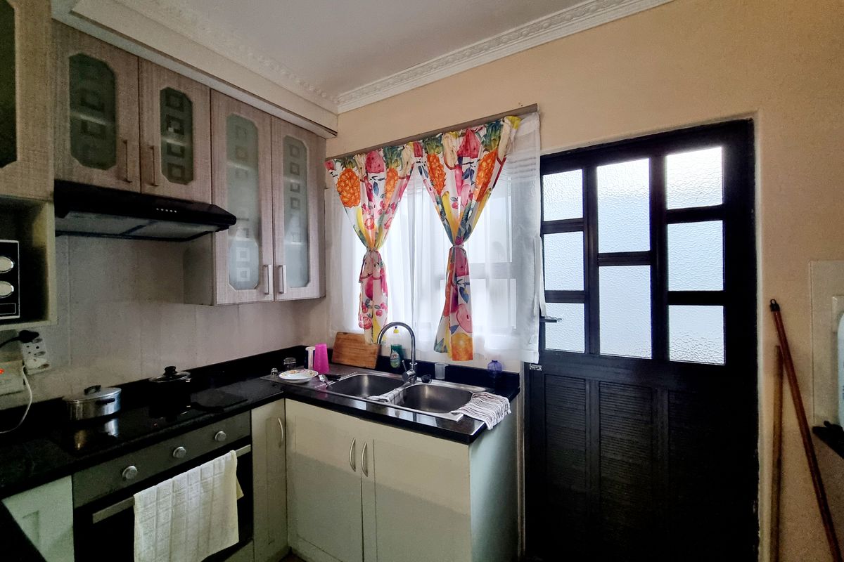 A functional kitchen featuring dark granite countertops, built-in oven, extractor fan, and double basin sink with direct access to an exterior door.