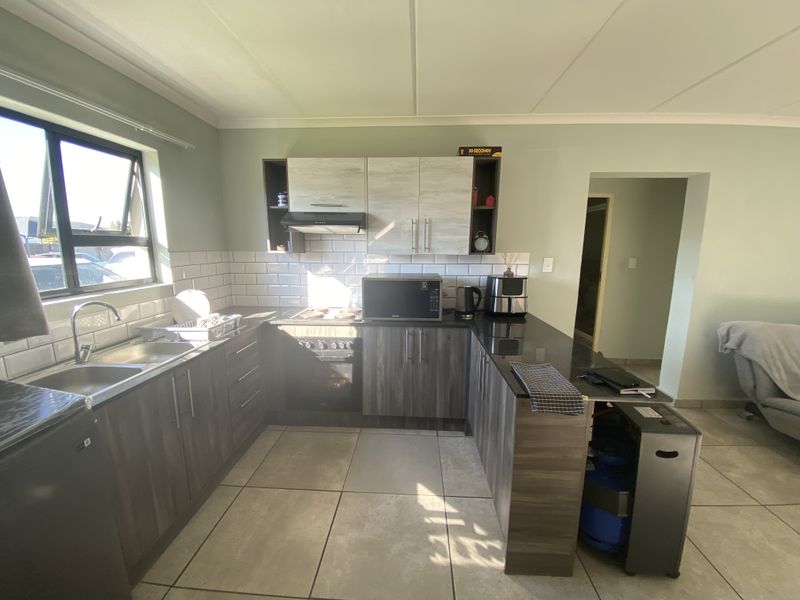 Modern U-shaped kitchen featuring dark wood-grain cabinetry, contrasting light upper cabinets, subway tile backsplash, and a breakfast bar peninsula.