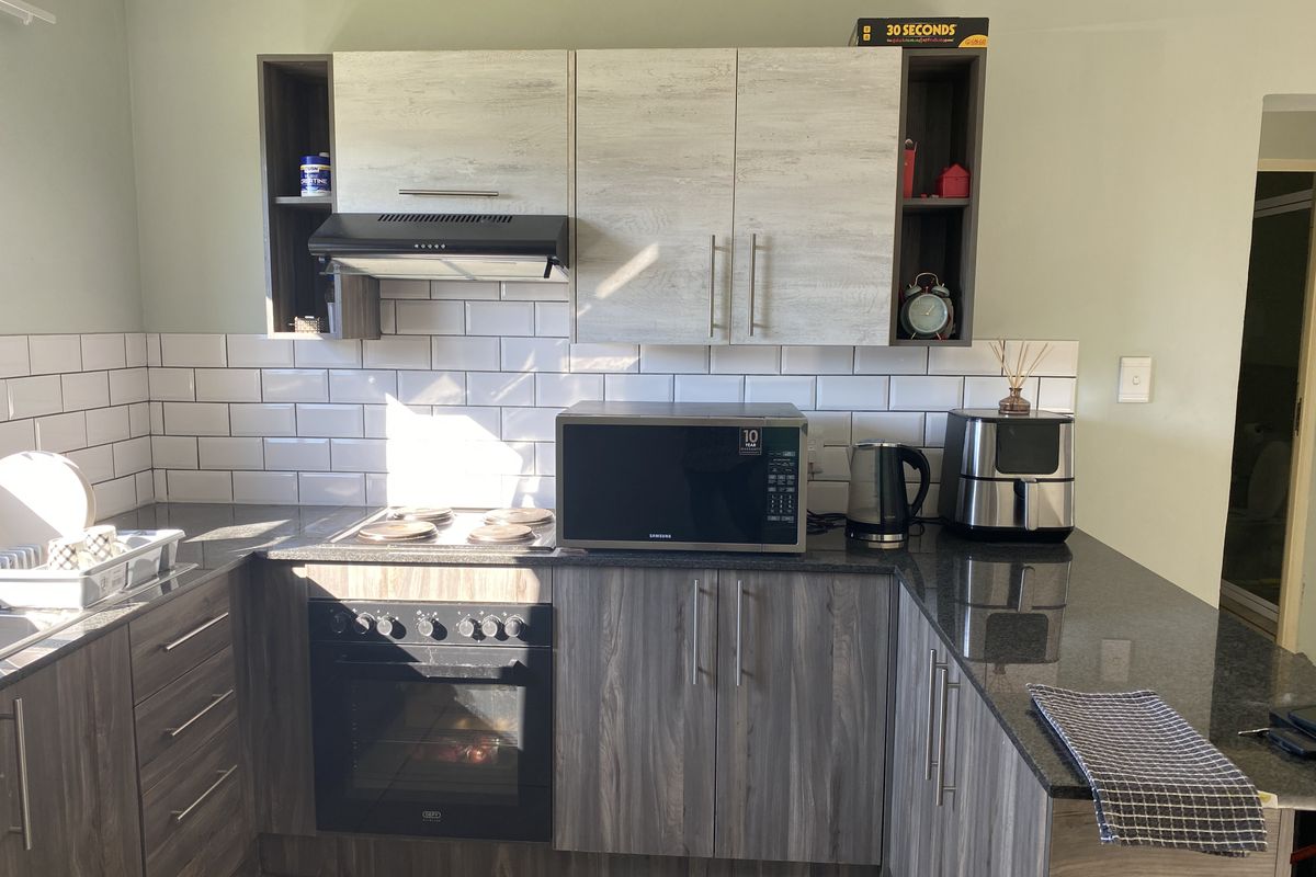 A modern kitchen featuring dark wood-grain lower cabinetry, light wood-grain upper cabinets, granite countertops, and a classic white subway tile backsplash.