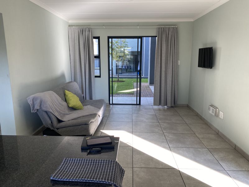 Open plan living area featuring large format floor tiles and sliding glass doors providing direct access to the rear garden.